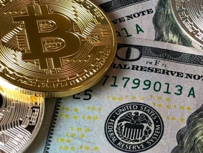 A close-up photo depicting Bitcoin coins on top of US dollar bills, symbolizing finance and cryptocurrency.
